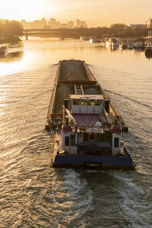 Quays of the Seine. View of the freight of a barge sailing along the Seine and The Defense district at sunset from Clichy Bridgeの写真素材