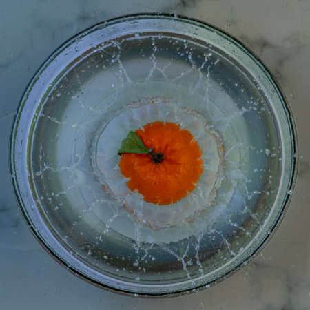 orange clementine dipped in a bowl of waterの写真素材