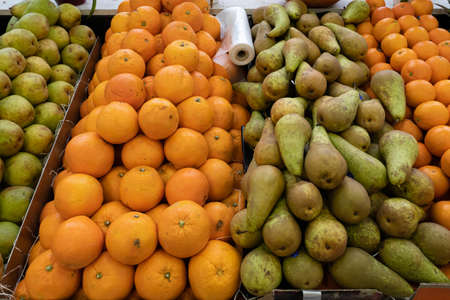 Primeur fruits and vegetables. Detail of mixed pears and oranges at a greengrocerの写真素材