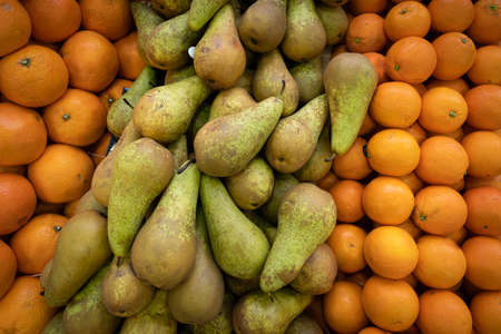 Primeur fruits and vegetables. Detail of mixed pears and oranges at a greengrocerの写真素材