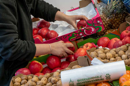 Primeur fruits and vegetables. A woman arranges apples on a stall in a greengrocerの写真素材