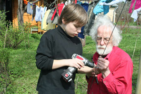 Young boy and grandfather working at backyardの写真素材