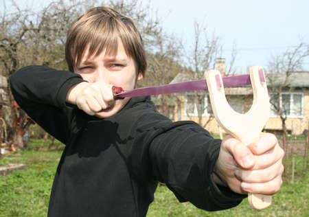 Young boy with catapult in a gardenの写真素材