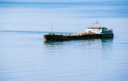 Cargo ship sailing with sand heaps の写真素材