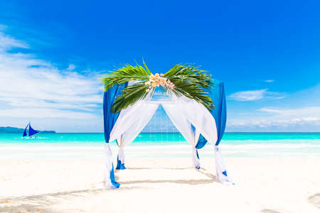Wedding ceremony on a tropical beach in blue. Arch decorated with flowers on the sandy beach. Wedding and honeymoon concept.の写真素材