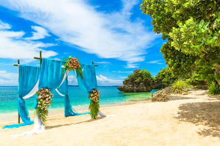 Wedding ceremony on a tropical beach in blue. Arch decorated with flowers on the sandy beach. Wedding and honeymoon concept.の写真素材