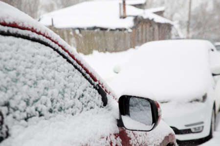 Snowfall in the city. Snow-covered cars on the street.の写真素材
