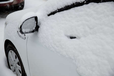 Snowfall in the city. Snow-covered cars on the street.の写真素材