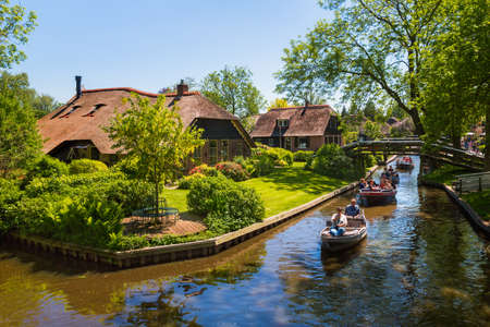 Giethoorn, Netherlands, May 30, 2021. Unknown people in the famous village of Giethoorn in the Netherlands with traditional dutch houses, gardens and water canals and wooden bridges is know as "Venice of the North"のeditorial素材