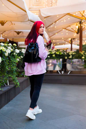 Beautiful red-haired girl in the evening on a lighted city streetの写真素材