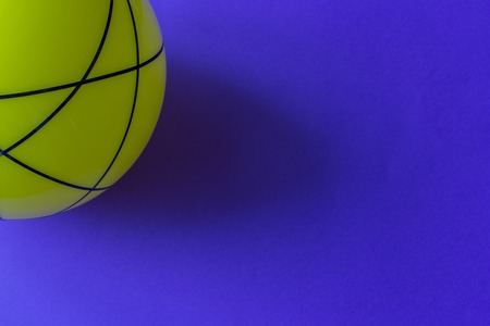 Big yellow glass ball on a blue background. Still life of striped yellow ball on bright blue table.の写真素材