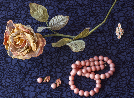 artificial rose with rose beads, on textile background.の写真素材