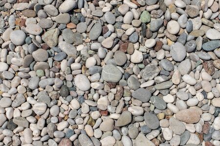 The texture of the pebbly beach. Background of small pebbles on the beach. Round pebbles