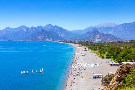 Panorama of a wide and long beach against the backdrop of mountains. Sea coast and a large beach. Blue sea with sailboats and a picturesque beach. Holidays in the Mediterranean.の写真素材