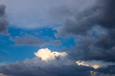 Bright blue sky through contrasting heavy clouds. The sun falls on the clouds after a thunderstorm....