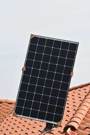 Young technician installing alternative energy photovoltaic solar panels
