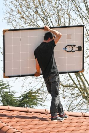Young technician installing alternative energy photovoltaic solar panelsの写真素材
