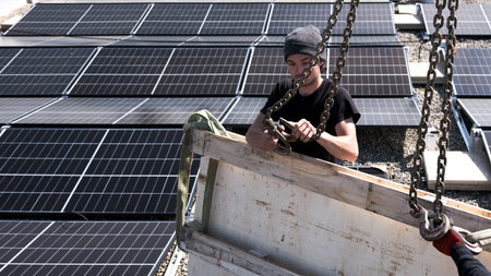 Male team engineers installing stand-alone solar photovoltaic panel system. Electricians mounting blue solar module on roof of company roof. Alternative energy conceptの写真素材
