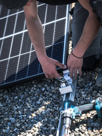 Male team engineers installing stand-alone solar photovoltaic panel system. Electricians mounting blue solar module on roof of company roof. Alternative energy conceptの写真素材