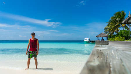 Man stands on the beach. Luxury island in Maldives, wooden jetty into blue tropical seaの写真素材