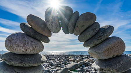 Stone arch on the shore of the Black Sea. Sun disk and blue sky on background, Sochiの写真素材