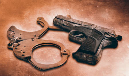 Gun and handcuffs on table  Photo in old color image styleの写真素材