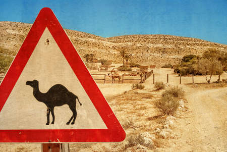 Road sign - camel and corral for camels. Negev desert. Photo textured in old color image style.の写真素材