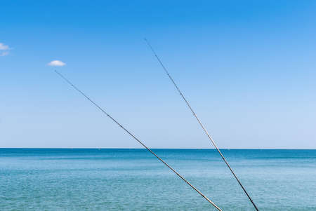 Fishing rods on the background of blue waterの写真素材