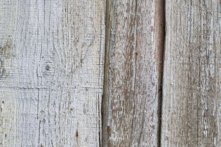 The blue paint is cracked on the wood surface and is falling off. Texture of old, vintage wood.