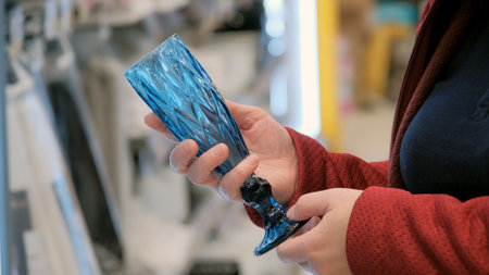 Girl in store chooses blue, glass wine glass. Close up shot. Concept of romance in design