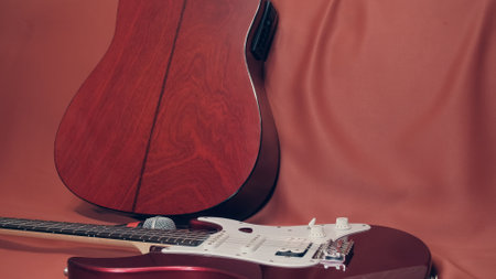 On the scarlet cloth is a purple electric guitar and microphone. In the background is an acoustic guitarの写真素材