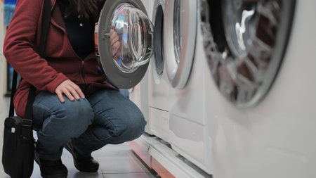 Woman in the electronics store opened the door of the washing machine. The concept of buying new...