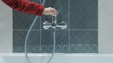 Woman in shop chooses water faucet. There are tiles all around. Concept of repair, construction and...