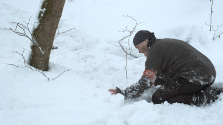 Special forces soldier sets tripwire trap. Disguises explosives under snowの写真素材