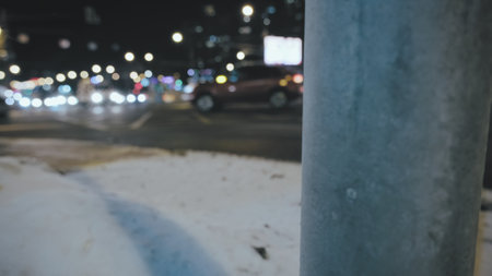 Dangerous location of the pole at the intersection of two major highways. The focus of the camera is on the pole, the cars and the road are in a blur in bokeh. Concept of road safety and night trafficの写真素材