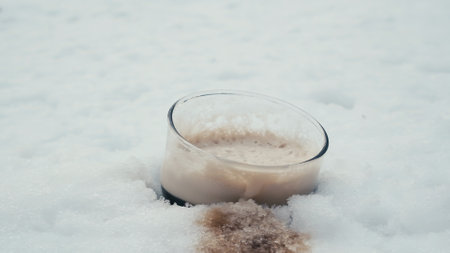 Glass of dark, strong Stout beer in snow. The concept of exotic bars and pubs in the open air in the...