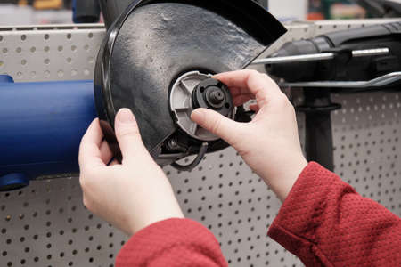 Woman in a building materials store chooses to buy an electric circular saw. Concept of women independence, feminism, gender equality, repair and construction. Hands close up shotの写真素材
