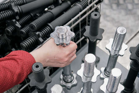 Girl in a store buys a neck for dumbbells. She carefully examines it. Concept of strength sports,...