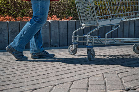 Girl on the street takes a grocery cart standing next to a large shopping center. The concept of a trip to the shopping and mallsの写真素材