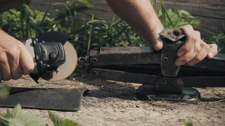 Man saws a lift jack with a circular saw. Concept of repair while traveling in field, without proper...