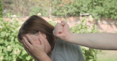 Frightened woman has black eye, man threatens her with his fist. Domestic violence, discrimination against women and social problems. Footage is staged, author is against any kind of violenceの写真素材