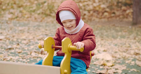 Small, cute child rides on a swing in the yard on a walk. The carousel rolls the baby. Lifestyle and active recreationの写真素材