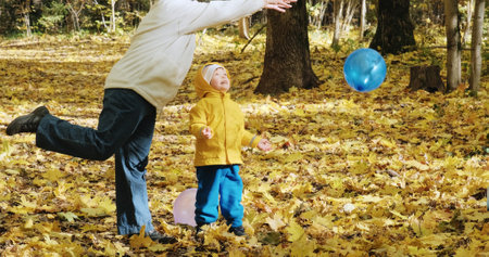 Small, cute child is playing with his mother in inflatable balloons. The concept of childhood, happy family and lifestyle. Autumn nature, clean air, active holidays on weekendsの写真素材