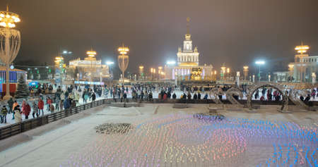 Moscow, Russia - december 05, 2021: Huge ice rink in Moscow exhibition of achievements of national economy - VDNH, evening. View from bridge to fountain of Friendship of peoples and central pavilionのeditorial素材