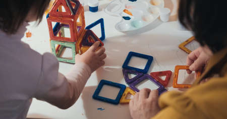 Child with his mother collects a magnetic constructor, a close up shot, a rear view, no faces are visible. The concept of development, joint family pastime and education of the child in a playful wayの写真素材