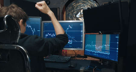Man, freelance trader on the stock exchange, sees growth of quotations on chart and is very happy. Home environment. Concept of game on the stock exchange for trading stocks, futures and bondsの写真素材