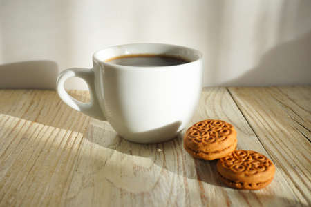 White cup of coffee and cookies on the wooden tableの写真素材