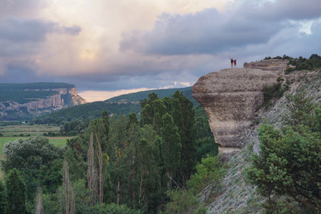 Couple on the top of a cliff at sunset in the mountainsの写真素材
