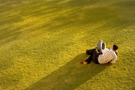Couple on grass relaxing as the sun sets.の写真素材