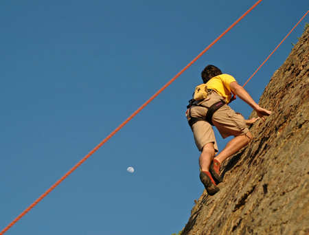 Climber climbs up California Cliff at Sunset and moon riseの写真素材
